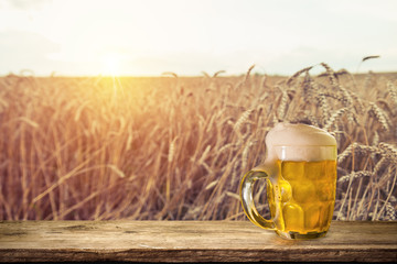 Beer keg with glasses of beer on rural countryside background