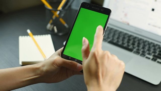 Business woman using a Smart phone Touchscreen CHROMA KEY- Close-up , Fingers make gestures touching and swiping the screen of a modern smartphone. A woman Holds a mobile With Green screen.