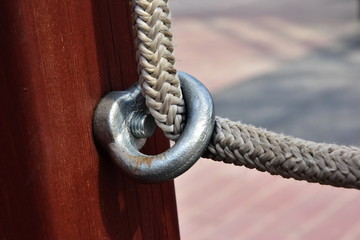 Stailess steel anchor loop. Detail of fixing the white nylon rope to the wooden beam on the...