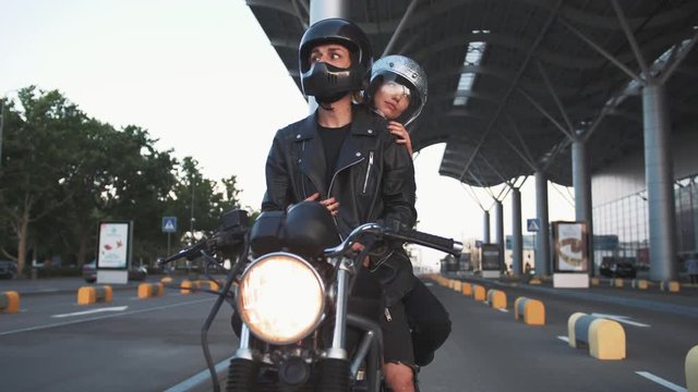 Young couple in helmets on motorcycle in city with urban background