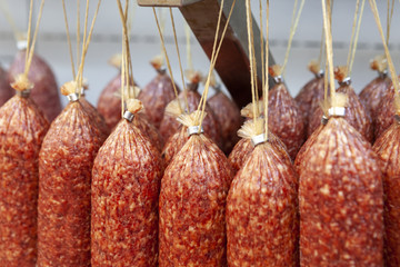 Hanging sticks of uncooked smoked sausage