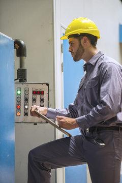Factory worker writing on clipboard in factory