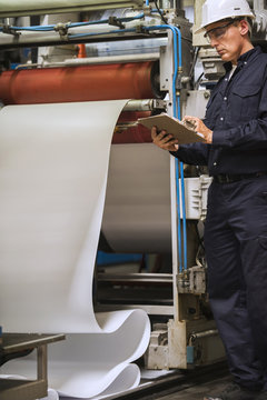 Factory worker writing on clipboard in factory