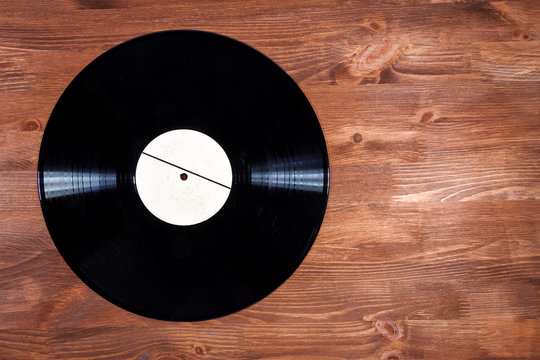 Black color vinyl record on brown wooden background
