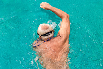 Top view of young Caucasian man swimming front crawl in a swimming pool
