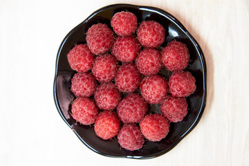 juicy fresh raspberries in a saucer top view