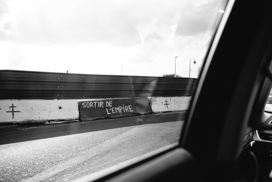 View from the car of graffiti sign on the peripherique highway border of Frexit and Exit from empire sign drawed by anty European Union members - black and white.
