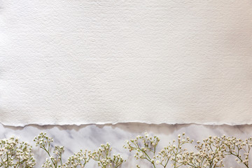 Copy space from white handmade paper on a marble table with white flowers