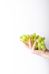 Hand holding green grapes on white background minimalism