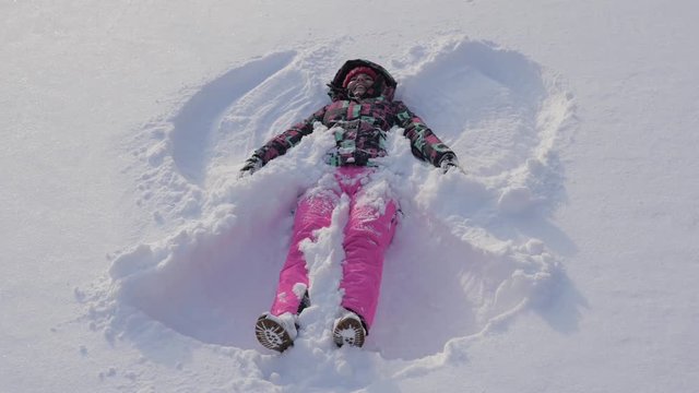 Happy Smiling Caucasian Woman Making Snow Angels In Winter Day