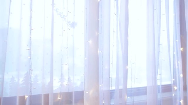 Decorated window for winter holidays. Christmas lights are on.
