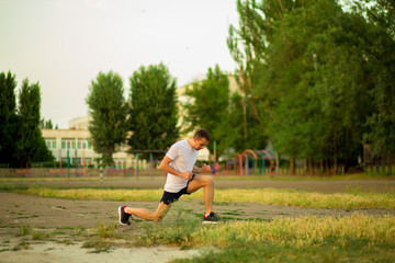 Obraz premium Athletic young man stretchng before run in nature. Healthy lifestyle