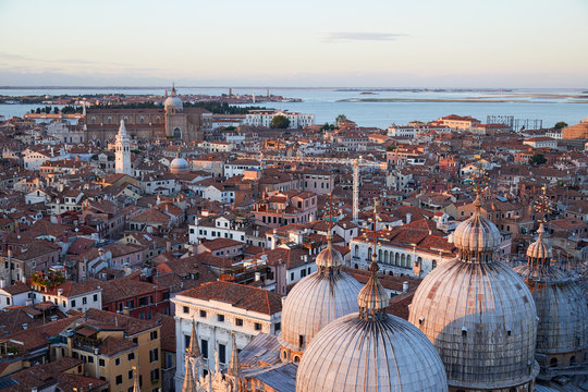 Aerial view of Venice rooftops and Saint Mark Basilica domes before sunset, Italy