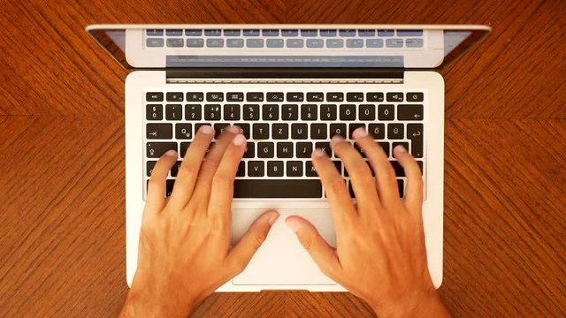 Male hands typing on the laptop keyboard Aerial View