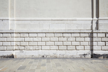 Empty tiled stone sidewalk and ancient white wall with molding