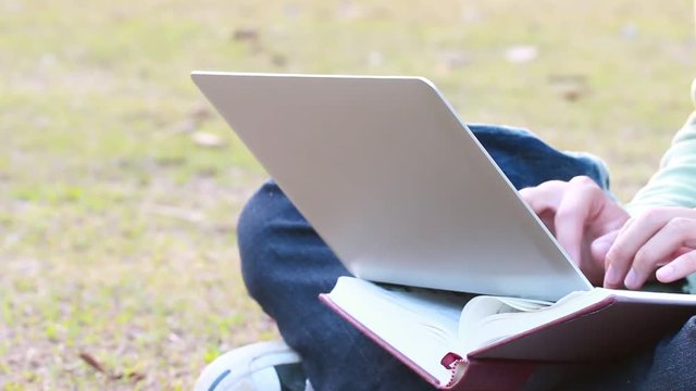 Education Learning Studying concept : Asian Boy students sitting for enjoy  searching, social with laptop for preparing final test exam at green grass in public park on vacation time in summer day.