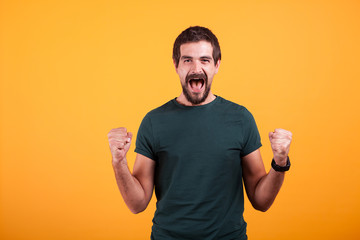 Fototapeta premium Joyful screaming excited man with his mouth open from emotions on orange yellow background. Portrait of expression and luck