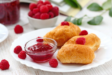Buns on a white plate with ripe raspberries and jam