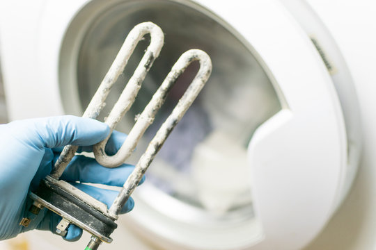 Washing Machine Repair. Hand Of Repairer With Turbular Electric Heating Element