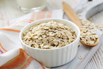 Oat flakes in a glass bowl and jug of milk