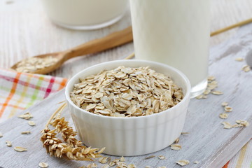 Oat flakes in a glass bowl and jug of milk
