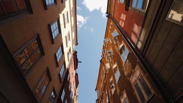 The beautiful narrow street of Stockholm. The open windows reflect the sky and the sun. Architecture of Europe