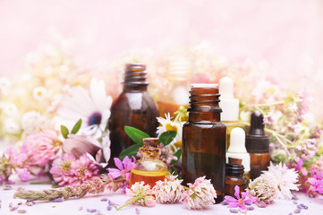 Essential oil bottles on medicinal flowers and herbs background, selective focus, toned