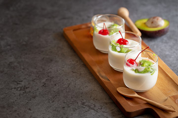 Glass of Cherry and avocado sliced in yogurt on wooden background