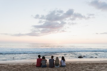 Group of friends sitting together in the beach