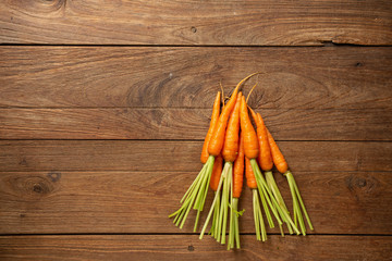 Fresh baby carrots on wooden cutting board and wooden background