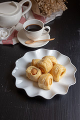 Tasty mini sausage in bread rolls and Cup of hot coffee on dark background
