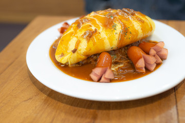 Flavored fried rice in an Omelet wrapping with sausages on wooden table