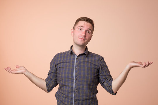 Studio portrait of confused handsome guy showing I have no idea gesture.