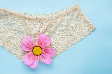 beige lace briefs on a blue background. concept of virginity