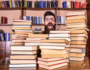 Nerd concept. Teacher or student with beard wears eyeglasses, sits at table with books, defocused....