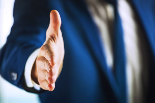 Closeup of business man with hand extended to handshake.