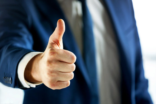 Closeup of business person showing thumb up.