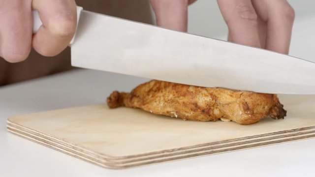 Cook cuts a piece from the grilled chicken fillet in slow motion