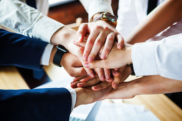 Closeup of a group of businesspeople joining their hands together.