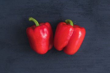 Two red fresh paprikas on dark blue wooden background