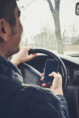 Fototapeta na wymiar Handsome Man using smartphone while driving the car