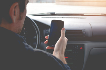 Businessman driving a car. Man with smartphone in the car