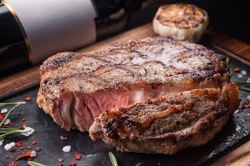 Meat steak medium, on a board with a stone and a bottle of wine