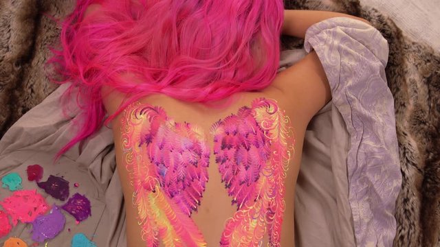 Lady with pink hair is modelling. Artwork on her body is almost finished.