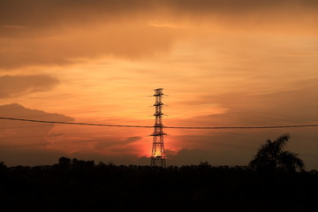 Beautiful sunset with an airplane in the background and the high voltage post at foreground 