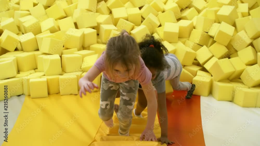Wall mural top view of three adorable children of different ethnicities climbing stairs of inflatable structure