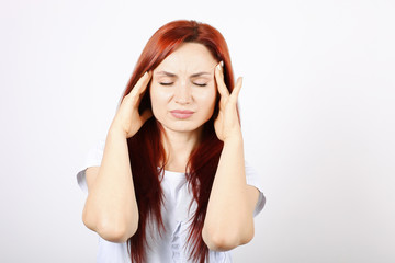 Beautiful redheaded young woman experiencing severe migraine writhing with pain. Pretty female...