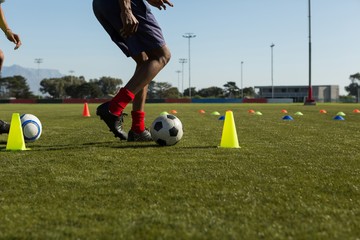 Soccer player dribbling the ball through cones