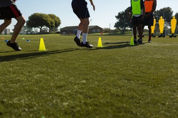 Soccer players dribbling the ball through cones