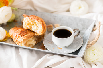Fresh Croissant, Cup of Coffee and Ranunculus Flowers. Breakfast